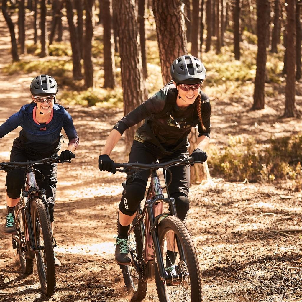 Zwei Personen genießen eine aufregende Fahrt auf E-Bikes im sonnigen Wald. Perfekt für Outdoor-Abenteuer und sportl