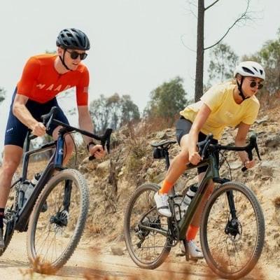 Zwei Personen fahren Cannondale Topstone Carbon Lefty Fahrräder auf Schotterweg