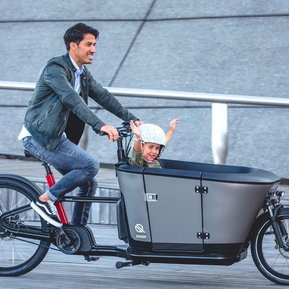 Ein Mann fährt auf dem Carqon Classic mit Kind in der Transportbox