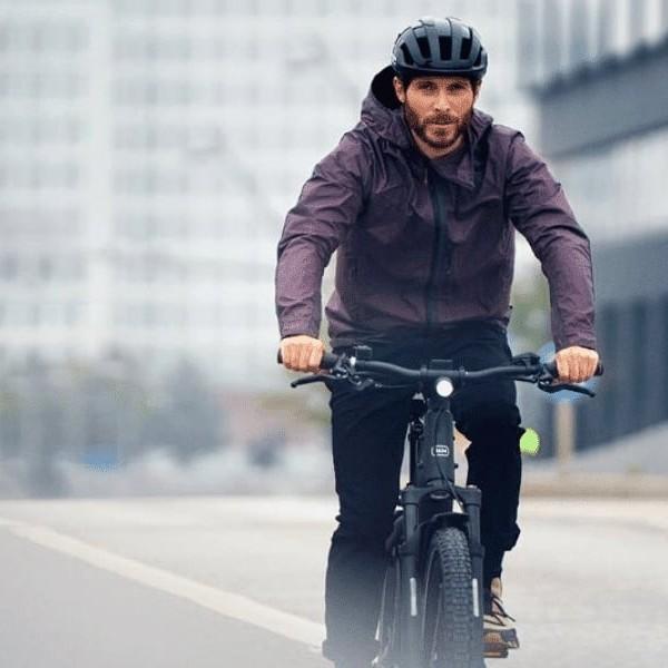 Mann fährt E-Bike auf städtischer Straße mit Helm