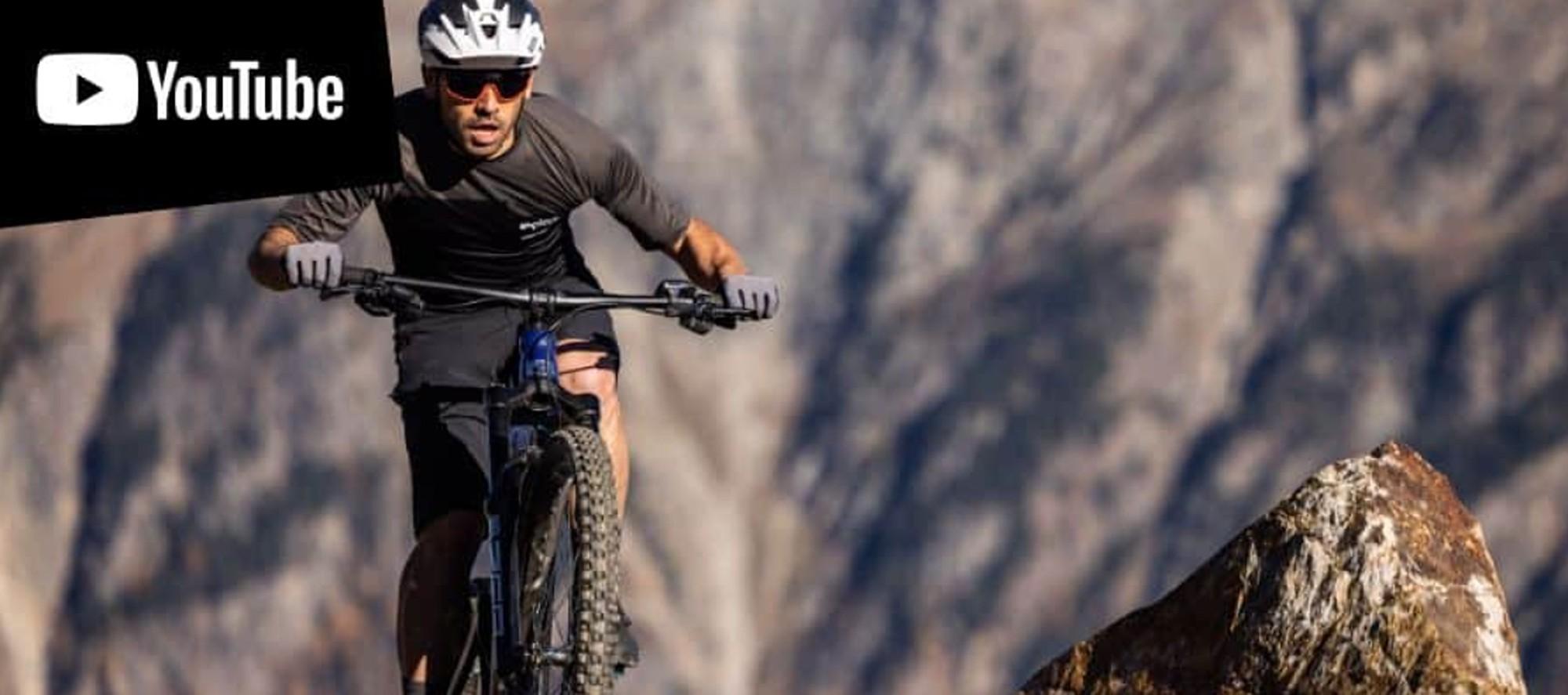 Das Bild zeigt einen Fahrer auf einem Corratec MTC E-Bike, der dynamisch über einen felsigen Untergrund fährt.