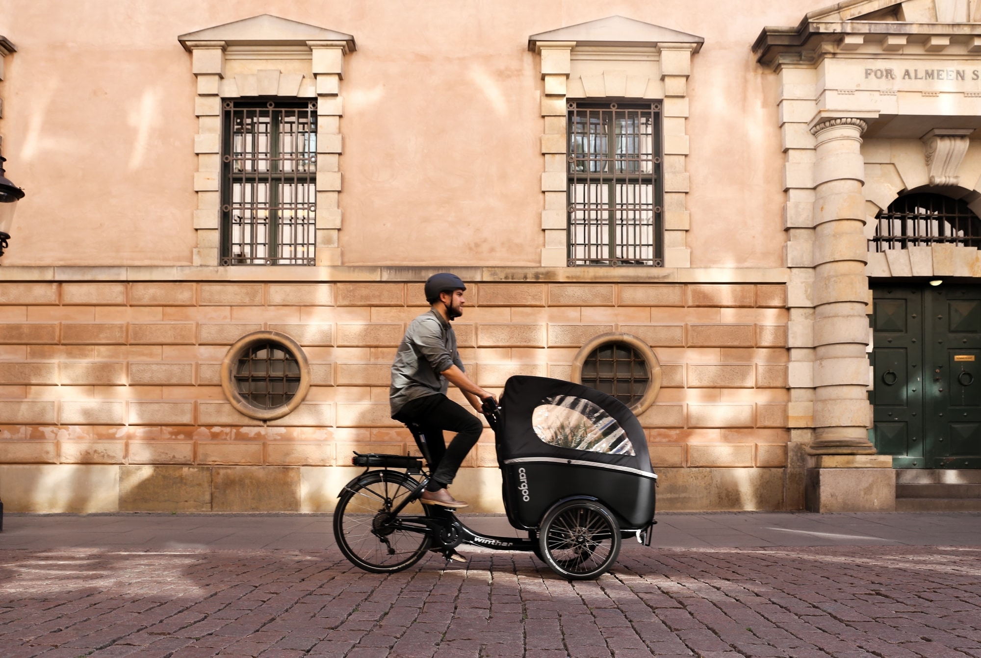 Stylisches Winther Kangaroo Lastenrad vor einem historischen Gebäude, ideal für urbane Mobilität und Transport.
