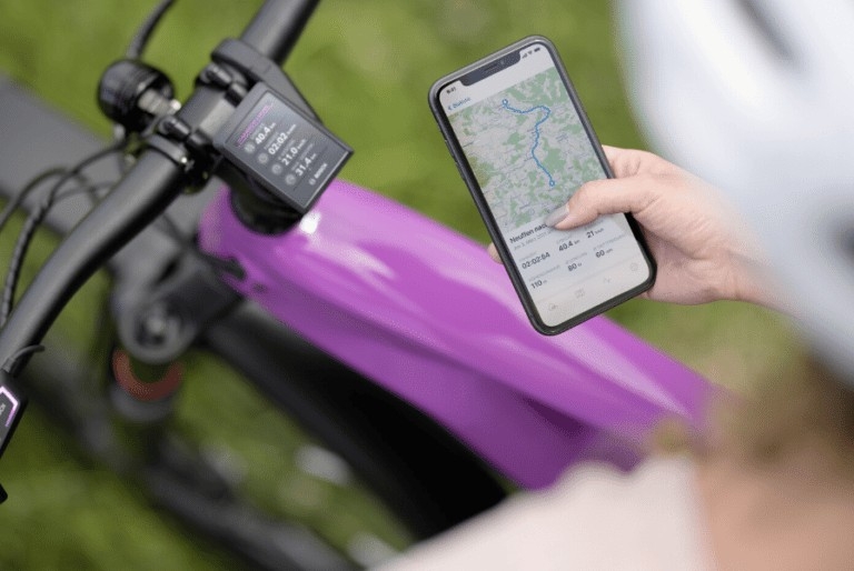 e-Bike mit Bosch Smart System Display mit Fahrdaten und Smartphone-Navigation, lila Rahmen betont Design.