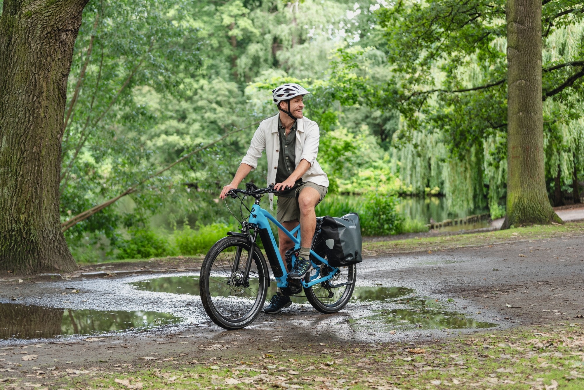 Ein Mann steht mit seinem Touren e-Bike in einer Parkfläche in Köln.