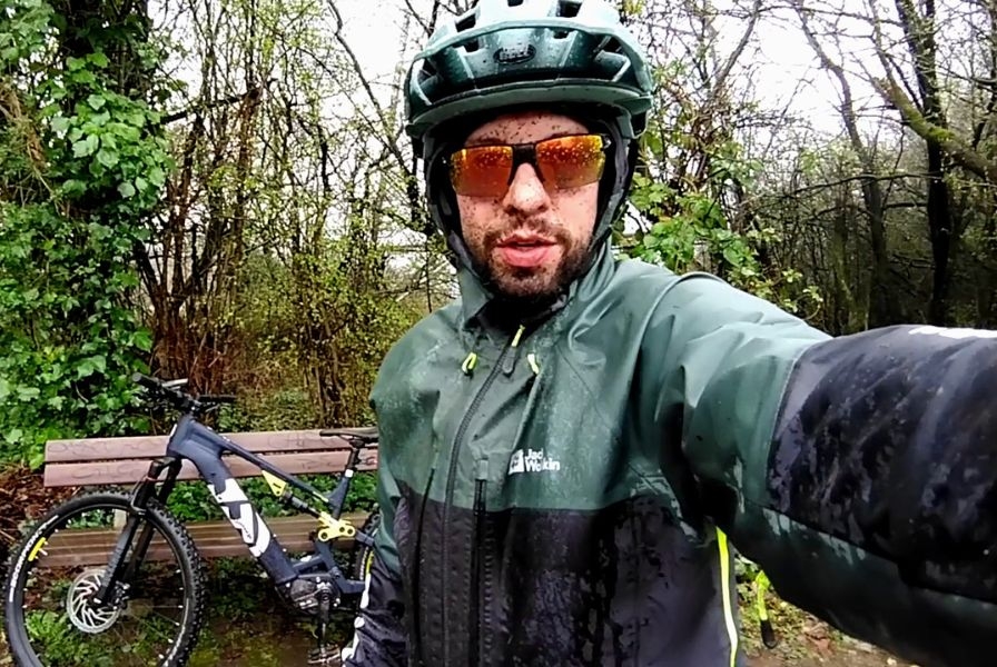 Ein Fahrradfahrer mit Husqvarna Light Cross im regnerischen Wald, ideal für Outdoor-Abenteuer.