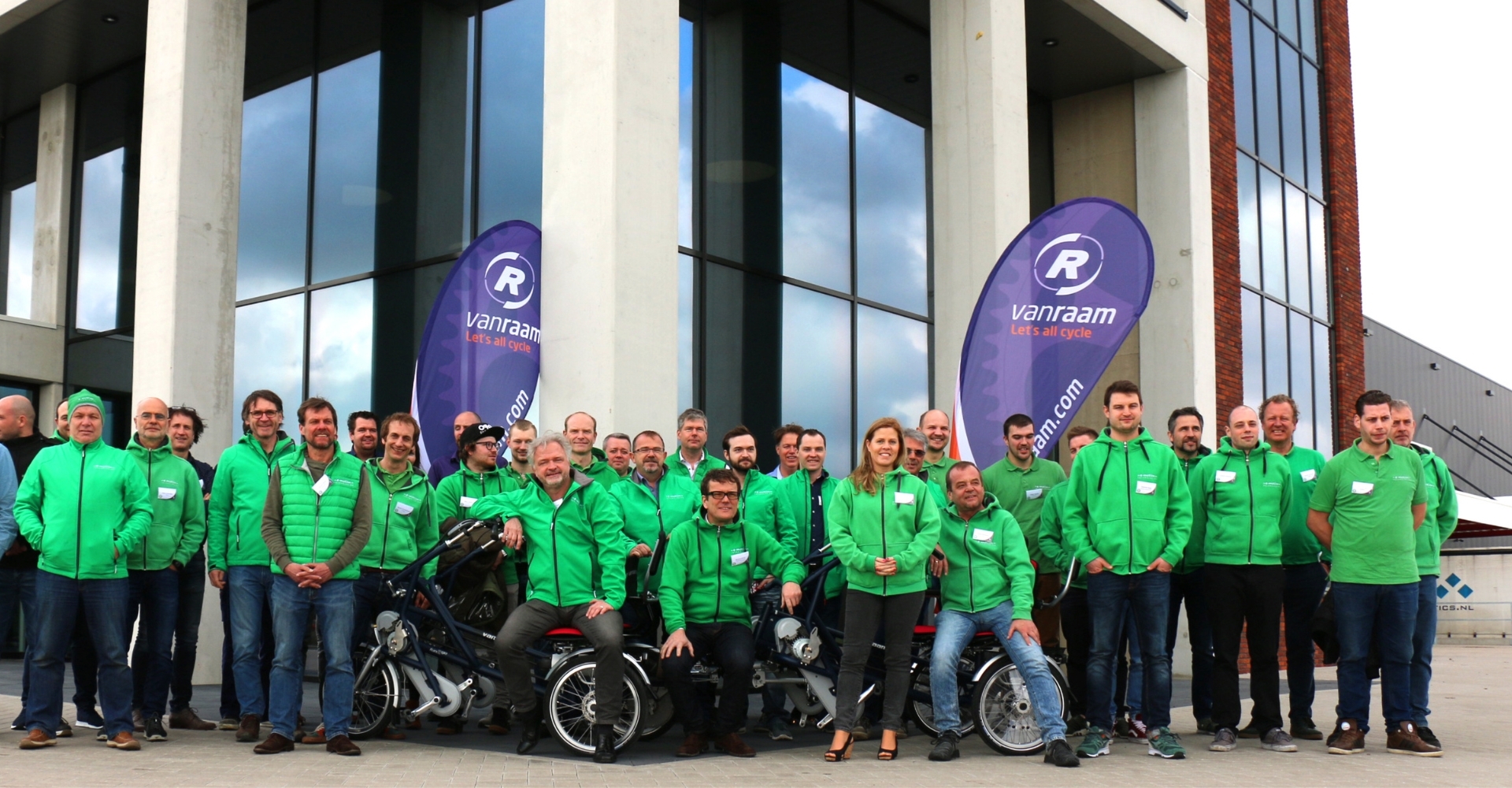 Die e-motion Van Raam-Dreiradhändler posieren für ein Gruppenfoto vor dem neuen Van Raam Sitz