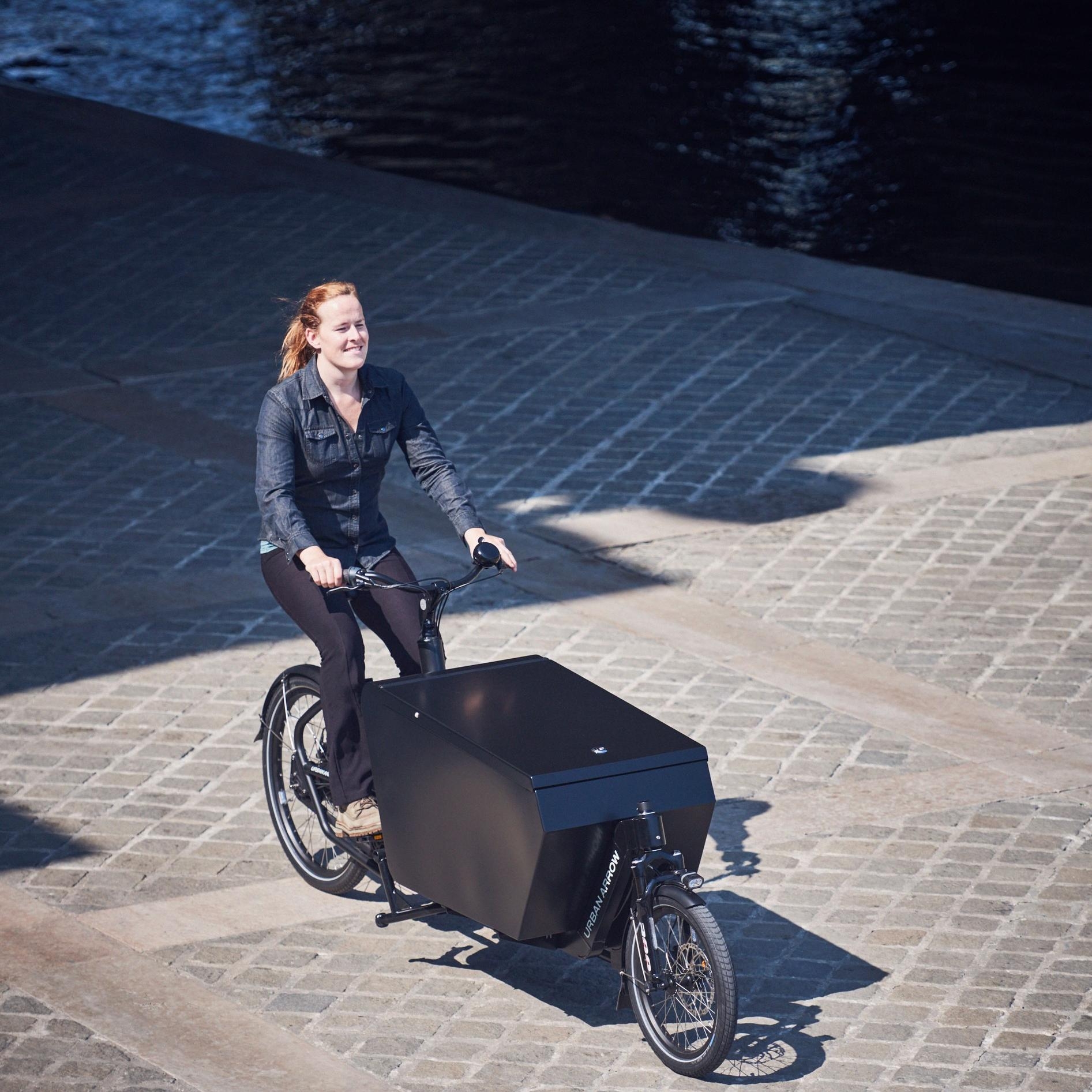 Eine Frau ist mit ihrem Urban Arrow Cargo e-Bike in Amsterdam, unterwegs zur International Dealer Convention.