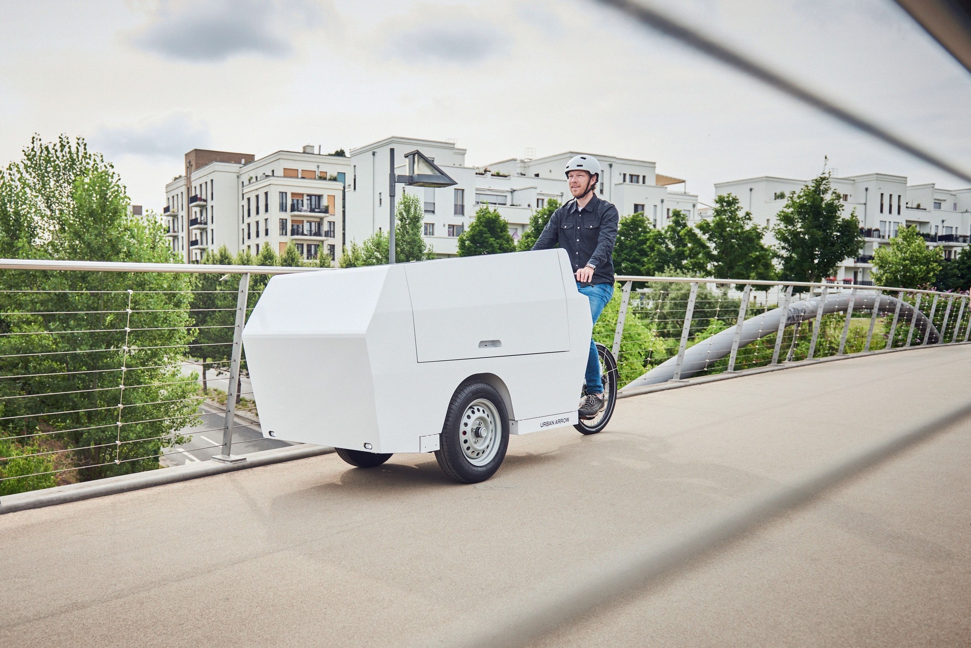 Mann fährt mit Urban Arrow Tender Lastenrad über eine Brücke