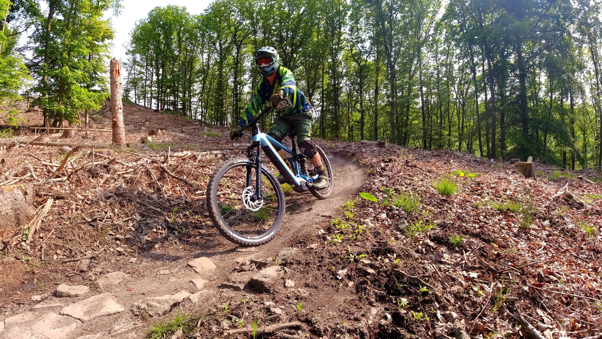 Ein Mountainbiker fährt auf einem Corratec e-Mountainbike einen Trail im Wald herunter.
