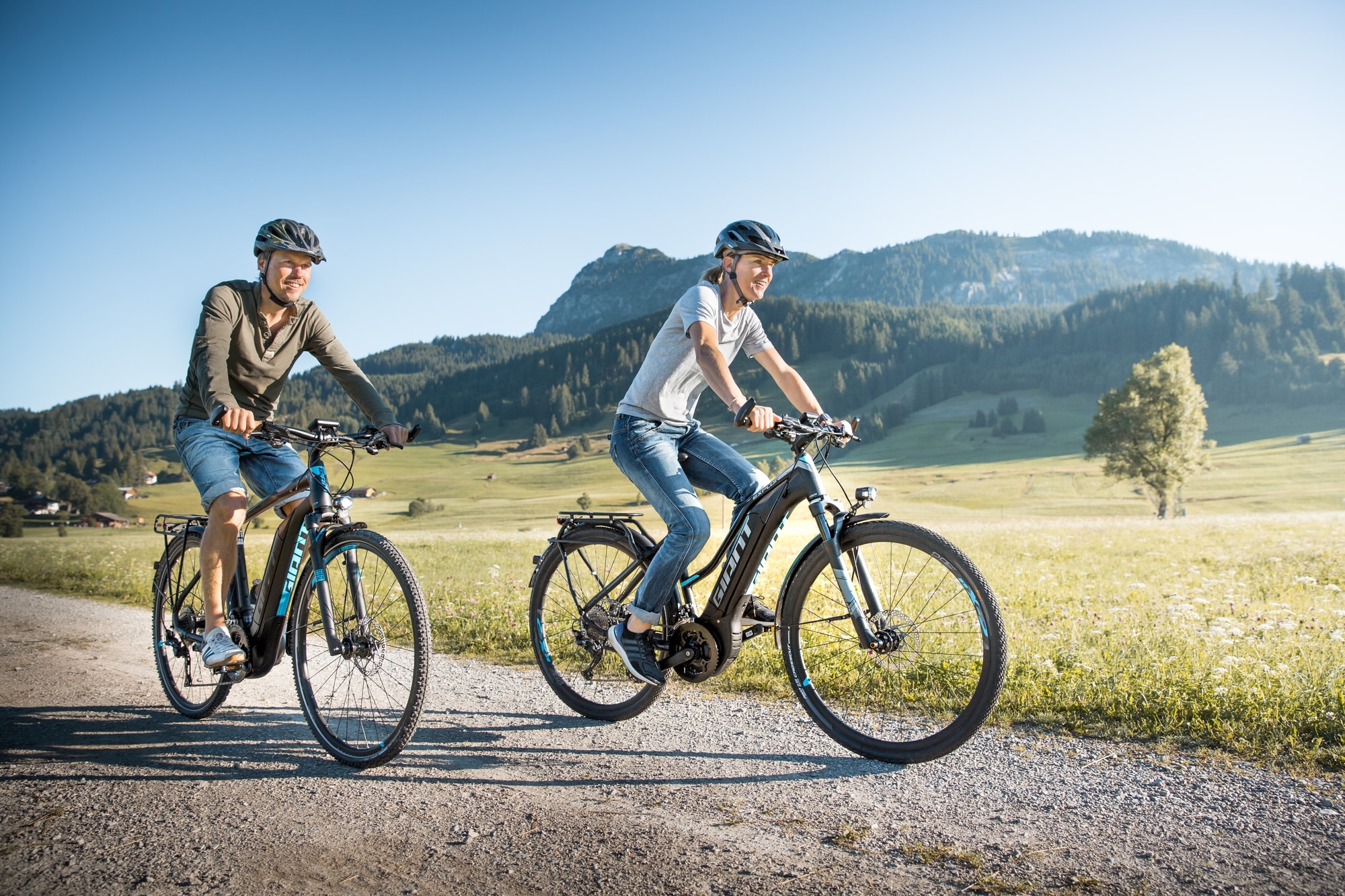 Zwei Personen genießen eine Fahrt durch die Natur auf Giant E-Bikes, ideal für Erkundungen und sportliche Ausflüge.