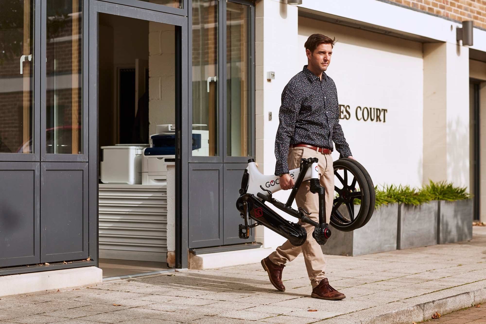 Ein Gocycle E-Bike wird von einem Mann getragen, praktisch für flexible urbane Mobilität. Ideal für Berufspendler.