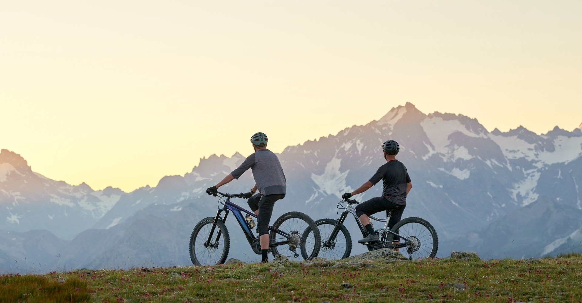 Zwei Personen sitzen auf Giant Trance e-MTBs und schauen auf die Berge