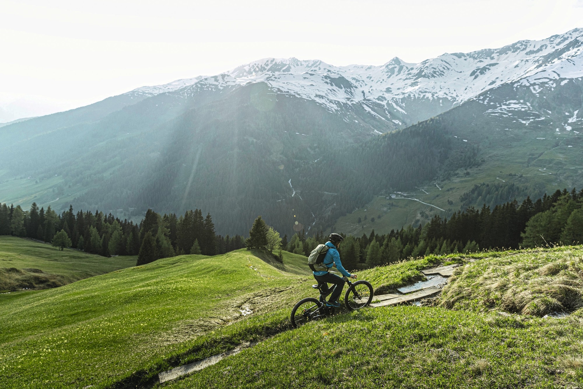 Das Bild zeigt einen Radfahrer, der auf einem Superdelite Mountain E-Bike ein malerisches alpines Gelände erkundet.