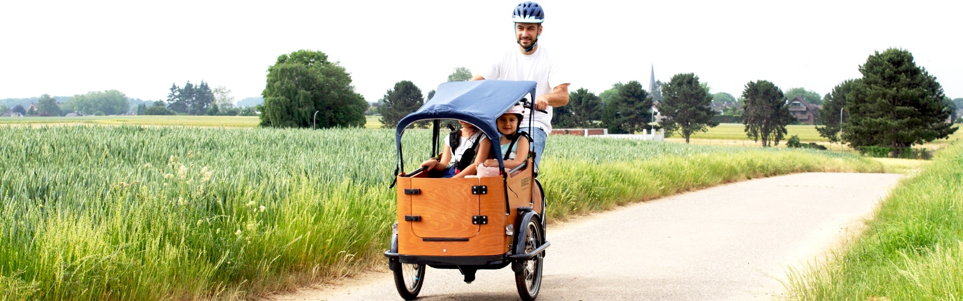 Christian fährt mit seinen Kindern im Babboe Go Mountain am Feld entlang