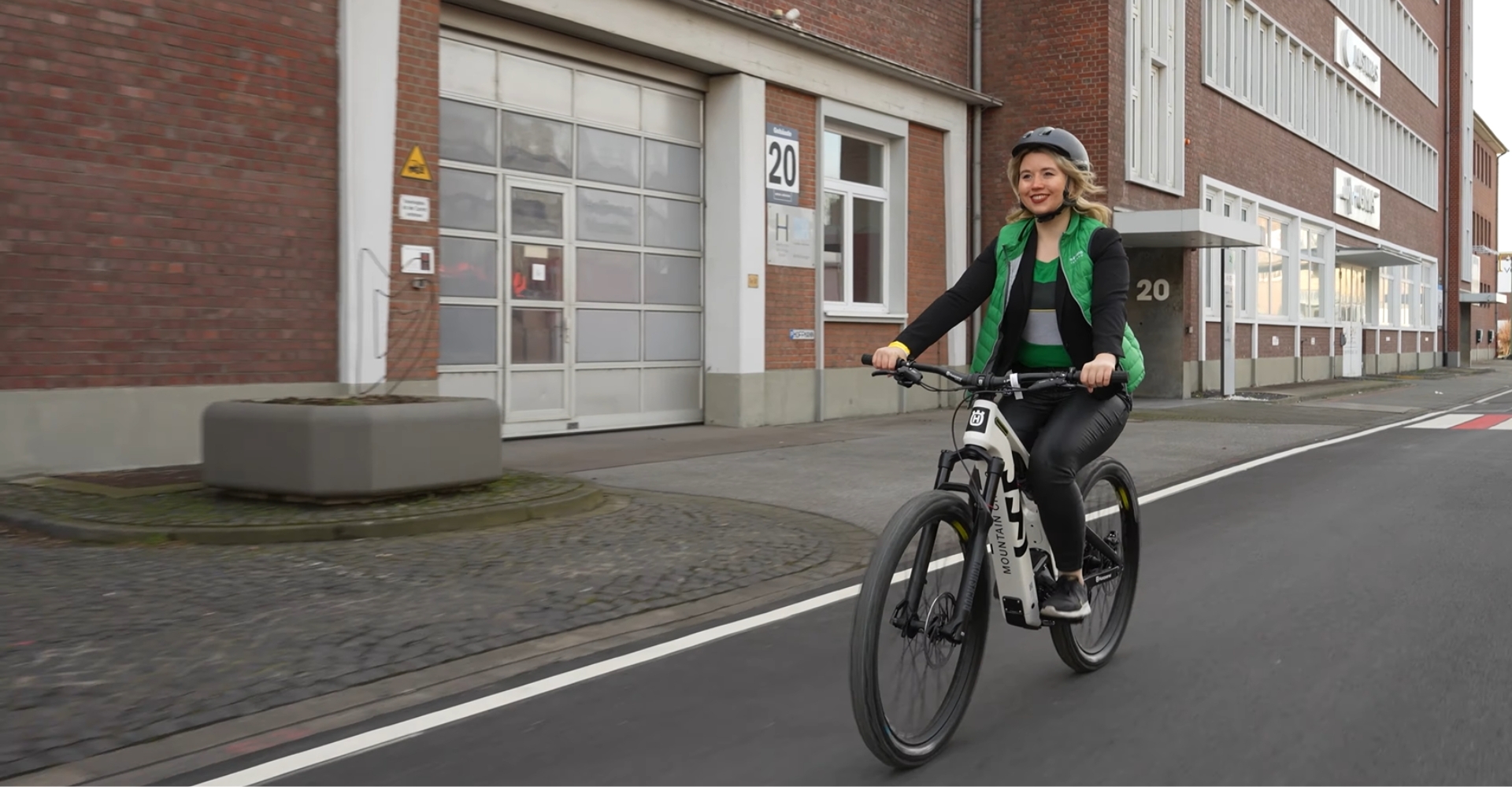 Eine Frau fährt mit einem Husqvarna City e-Bike von 2023 durch ein Industriegebiet