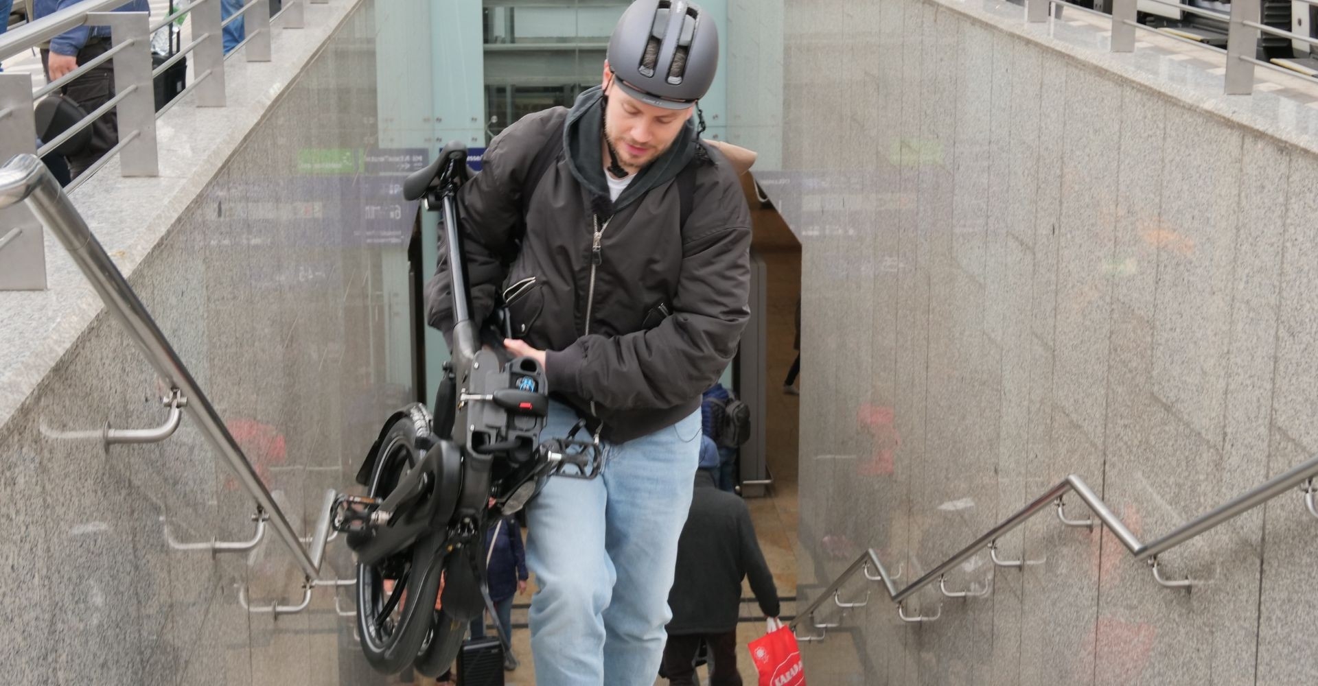 Mann trägt Brompton Klapprad die Treppen am Bahnhof hoch