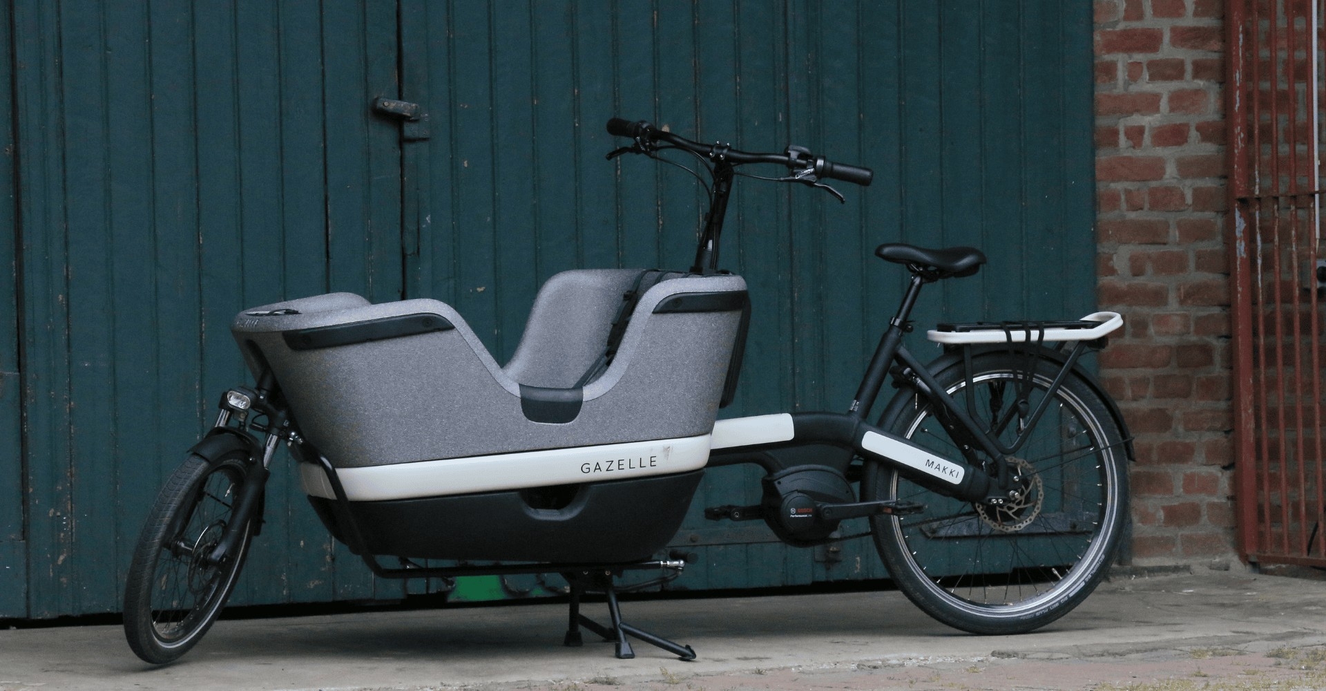 Das Lastenrad Modell Gazelle Makki Load steht vor einer grünen Scheunentüre