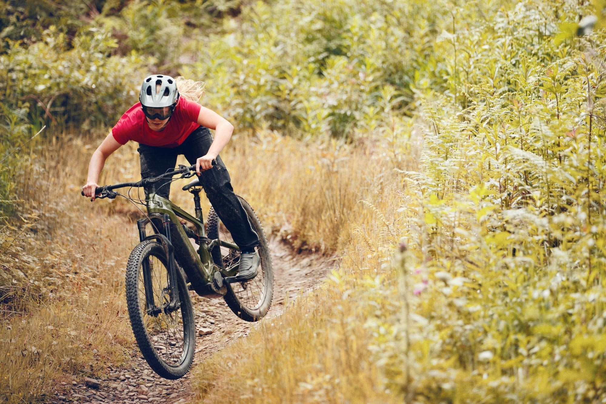 Ein Mountainbiker fährt auf dem Cannondale Habit Neo e-Mountainbike nähe Gießen einen Hügel hinab.
