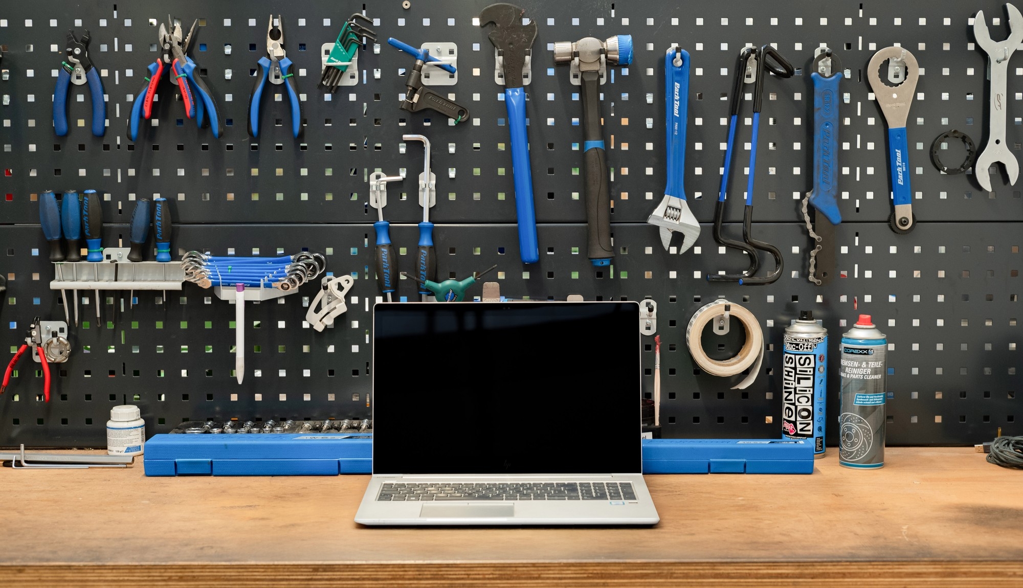 Eine Werkbank in der Werkstatt mit unterschiedlichem Werkzeug und einem Laptop