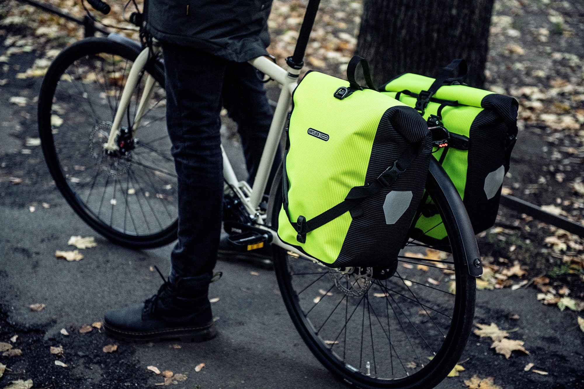 Das Bild zeigt ein Fahrrad, das mit zwei auffälligen, leuchtend Ortlieb Back Roller HV Taschen ausgestattet ist.
