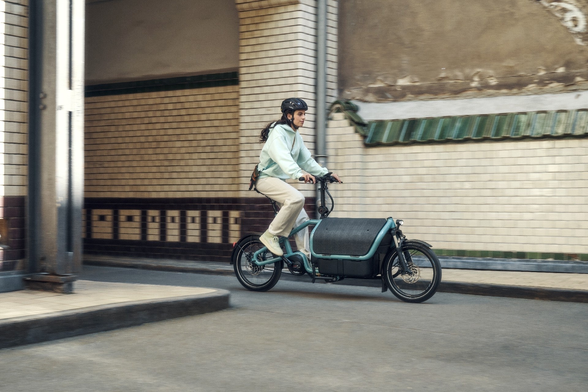 Das Bild zeigt eine Frau auf einem Carrie Lastenrad der Marke Riese & Müller.