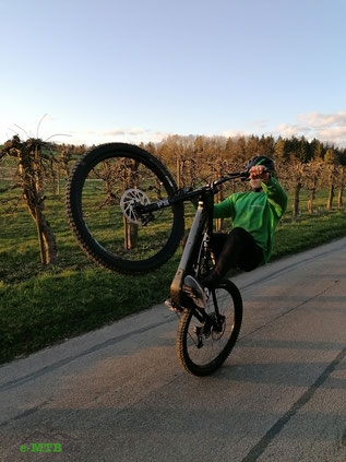 Entdecke das Specialized Levo SL E-Bike beim Wheelie in malerischer Landschaft - perfekte Balance zwischen Performa
