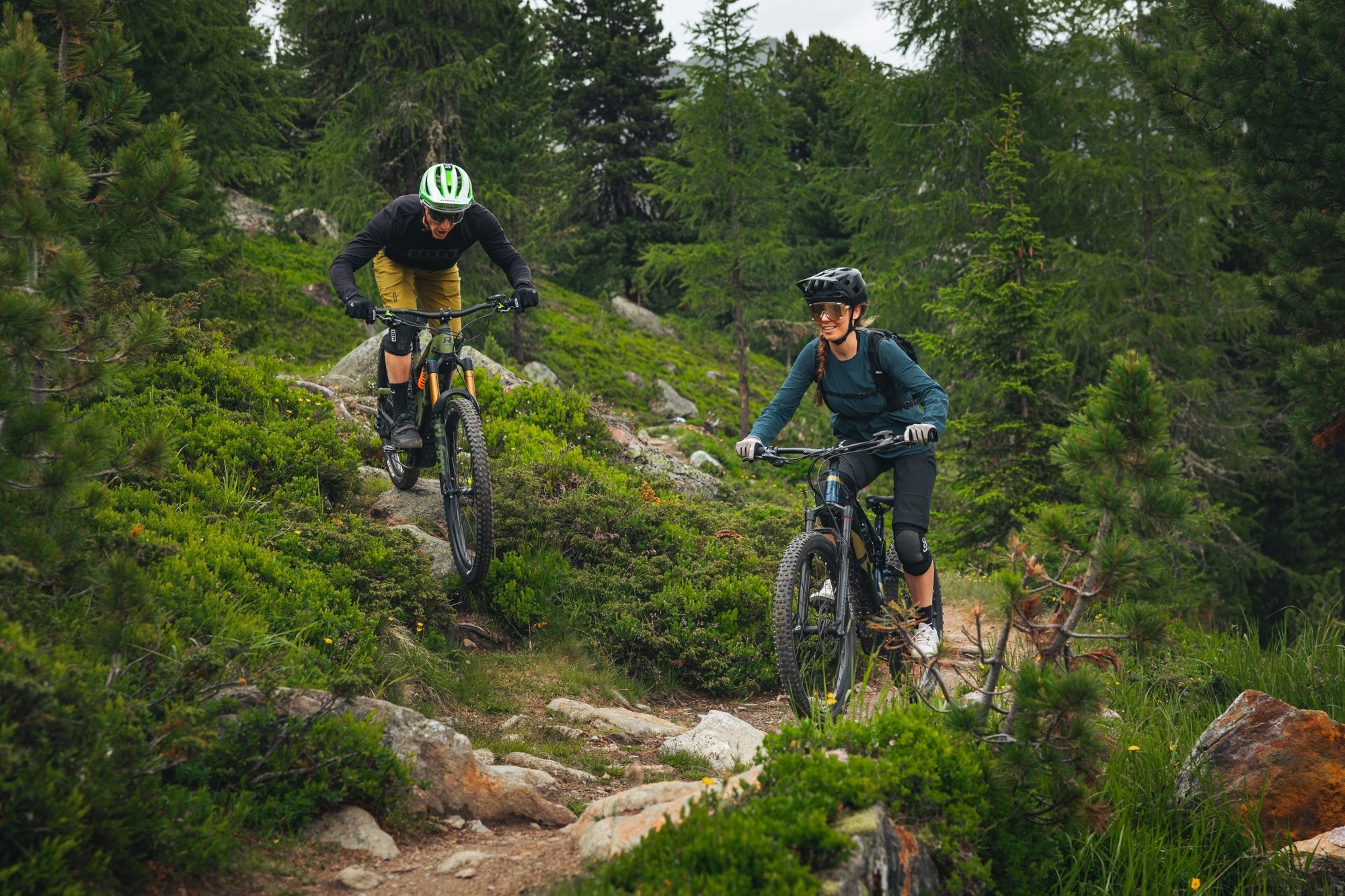 Ein Mountainbiker-Paar fährt auf dem R Raymon Fullray e-Nine Trailbike einen Berg herunter.