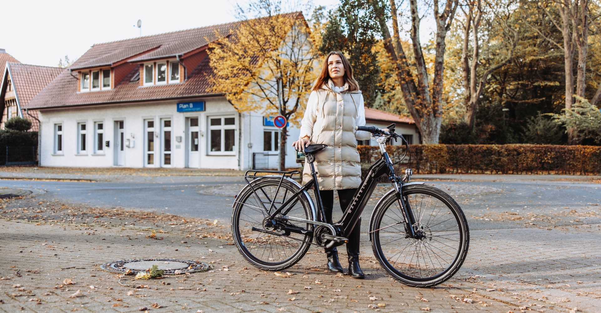 Eine Frau steht mit einem e-Bike vor einer herbstlichen Kulisse